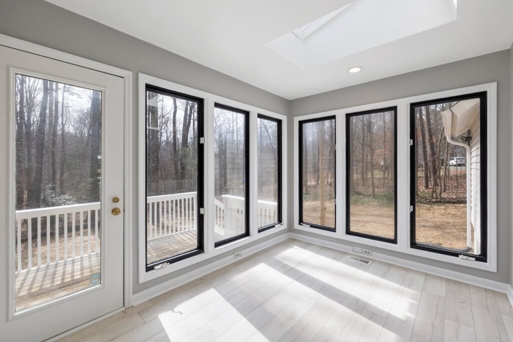Spacious sunroom with floor-to-ceiling windows offering tranquil forest views. Spacious sunroom with floor-to-ceiling windows offering tranquil forest views.
